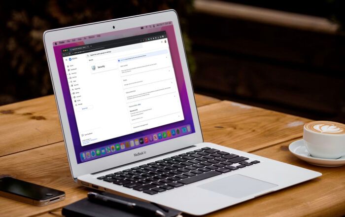 Laptop showing the Google Admin console website sitting on wooden table with a notebook, cellphone, and a cappuccino.
